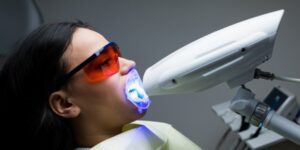 A patient undergoing professional teeth whitening at 92 Dentistry in Portland, OR. The procedure uses a specialized light to enhance whitening results.