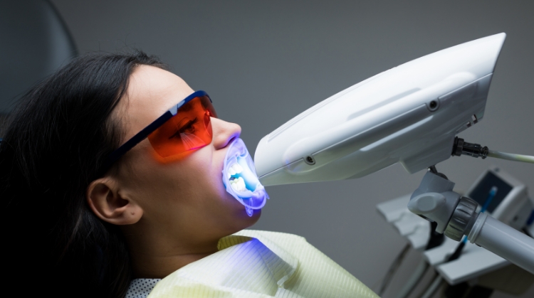 A patient undergoing professional teeth whitening at 92 Dentistry in Portland, OR. The procedure uses a specialized light to enhance whitening results.