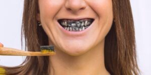 Woman brushing teeth with charcoal toothpaste, showing black-stained smile – 92 Dentistry, Portland, OR.