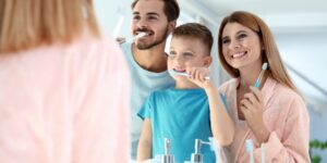 Smiling family brushing teeth together to prevent cavities in kids – 92 Dentistry
