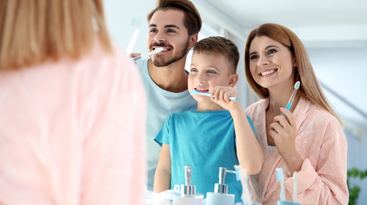 Smiling family brushing teeth together to prevent cavities in kids – 92 Dentistry